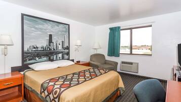 A hotel room with a bed, a desk, a chair, a window with curtains, a wall-mounted air conditioner, and a cityscape painting.