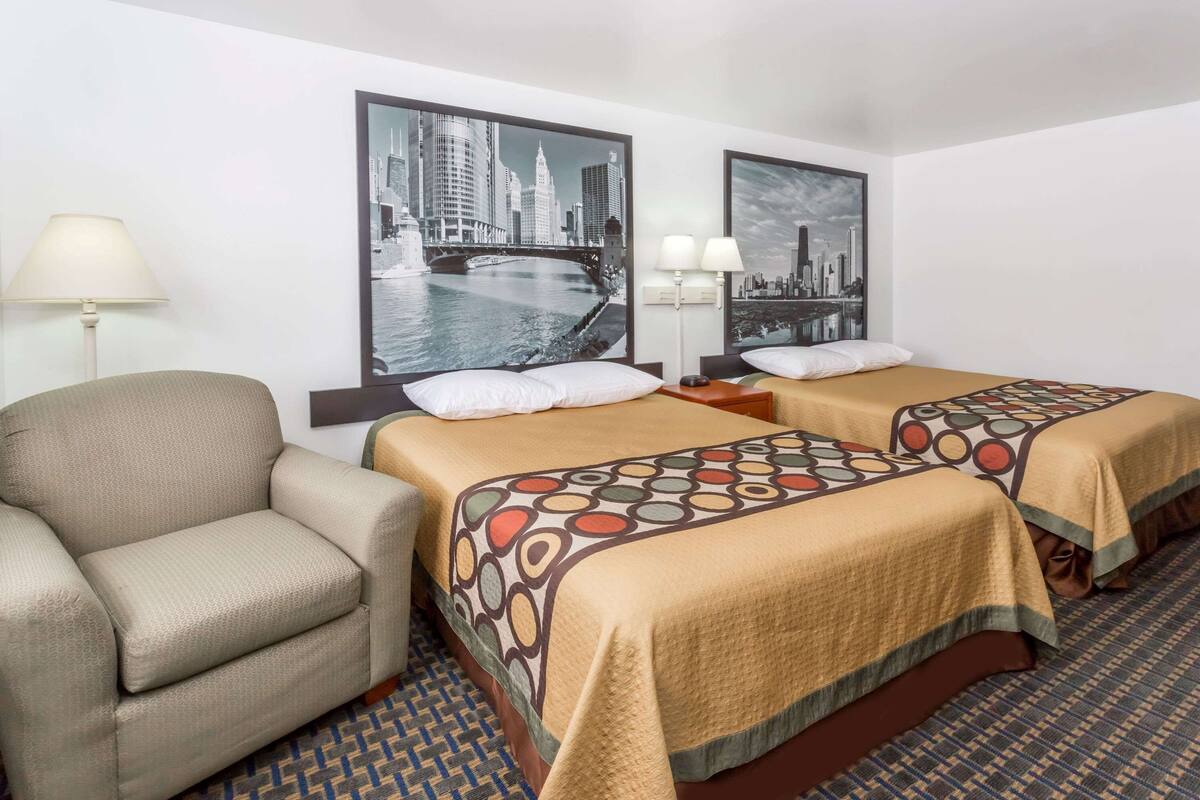 Een hotelkamer met twee bedden, een bank en een lamp.