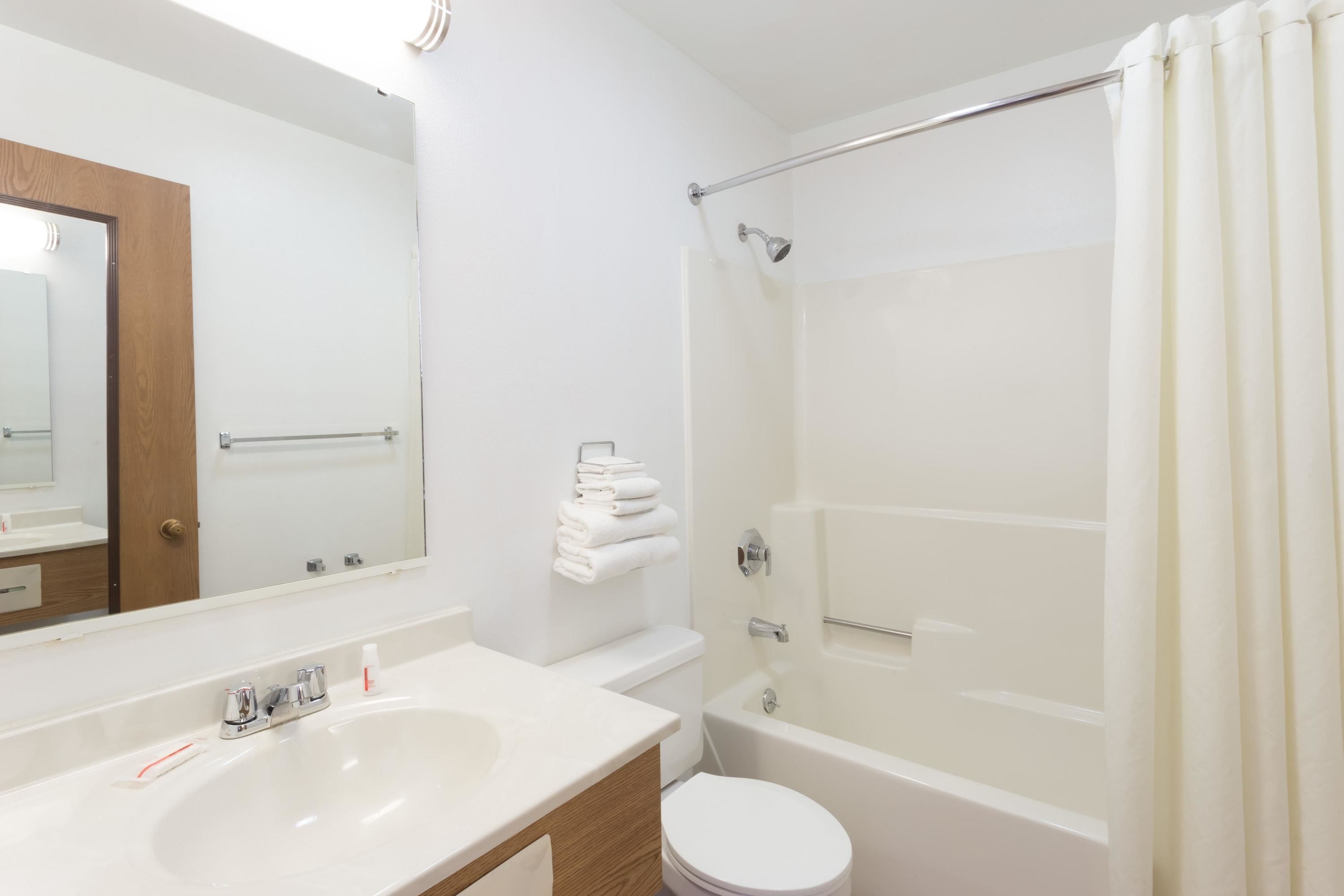 A modern bathroom with a white sink, mirror, toilet, and bathtub.
