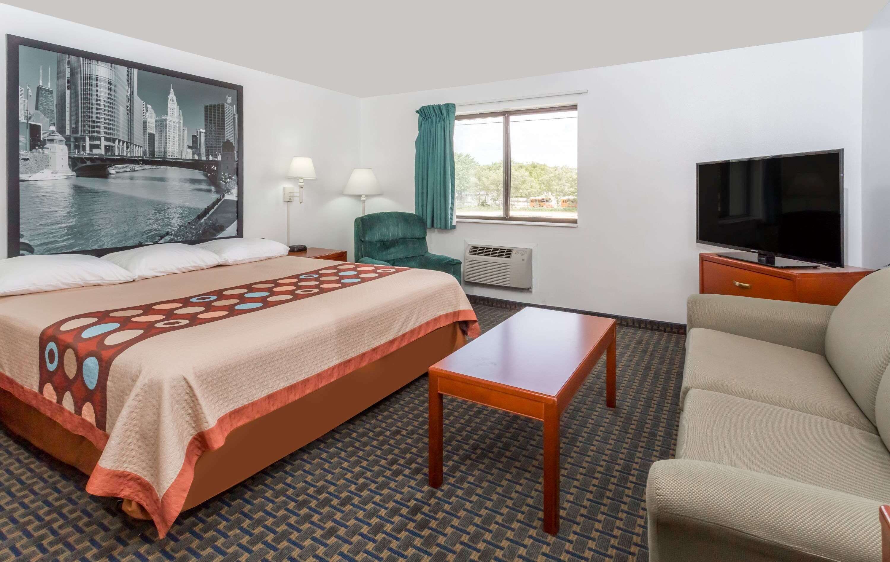 Ett hotellrum med en stor säng, en TV, en soffa och ett skrivbord.