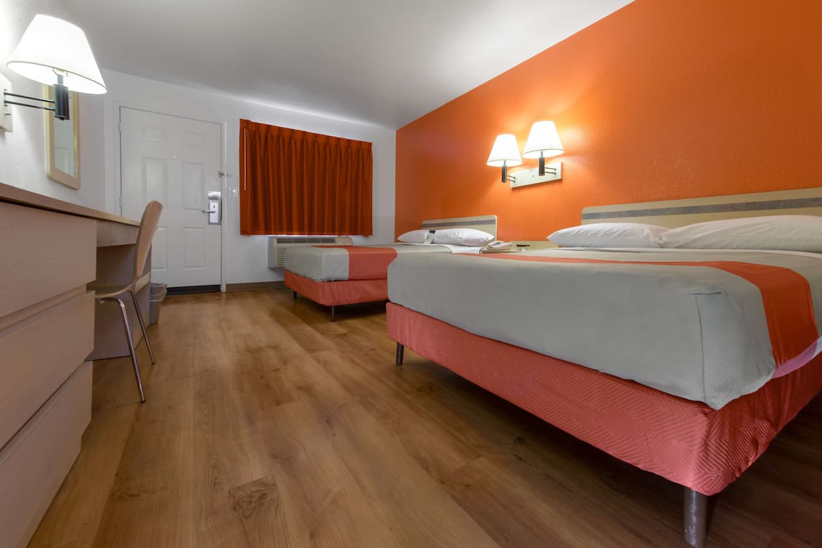 A hotel room with two beds, a desk, and a chair.