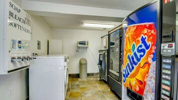 A laundry room with a washing machine, a dryer, a microwave, and a soda vending machine.
