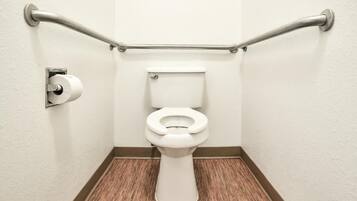 Een badkamer met een wit toilet, toiletpapier en een handgreep.
