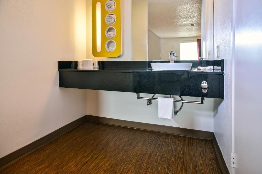 A modern bathroom with a black countertop, a white sink, and a mirror.