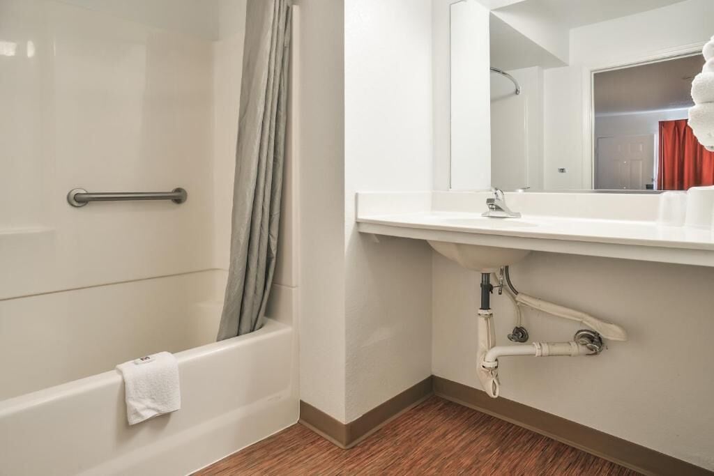 Un baño con bañera, cortina de ducha, lavamanos y espejo.