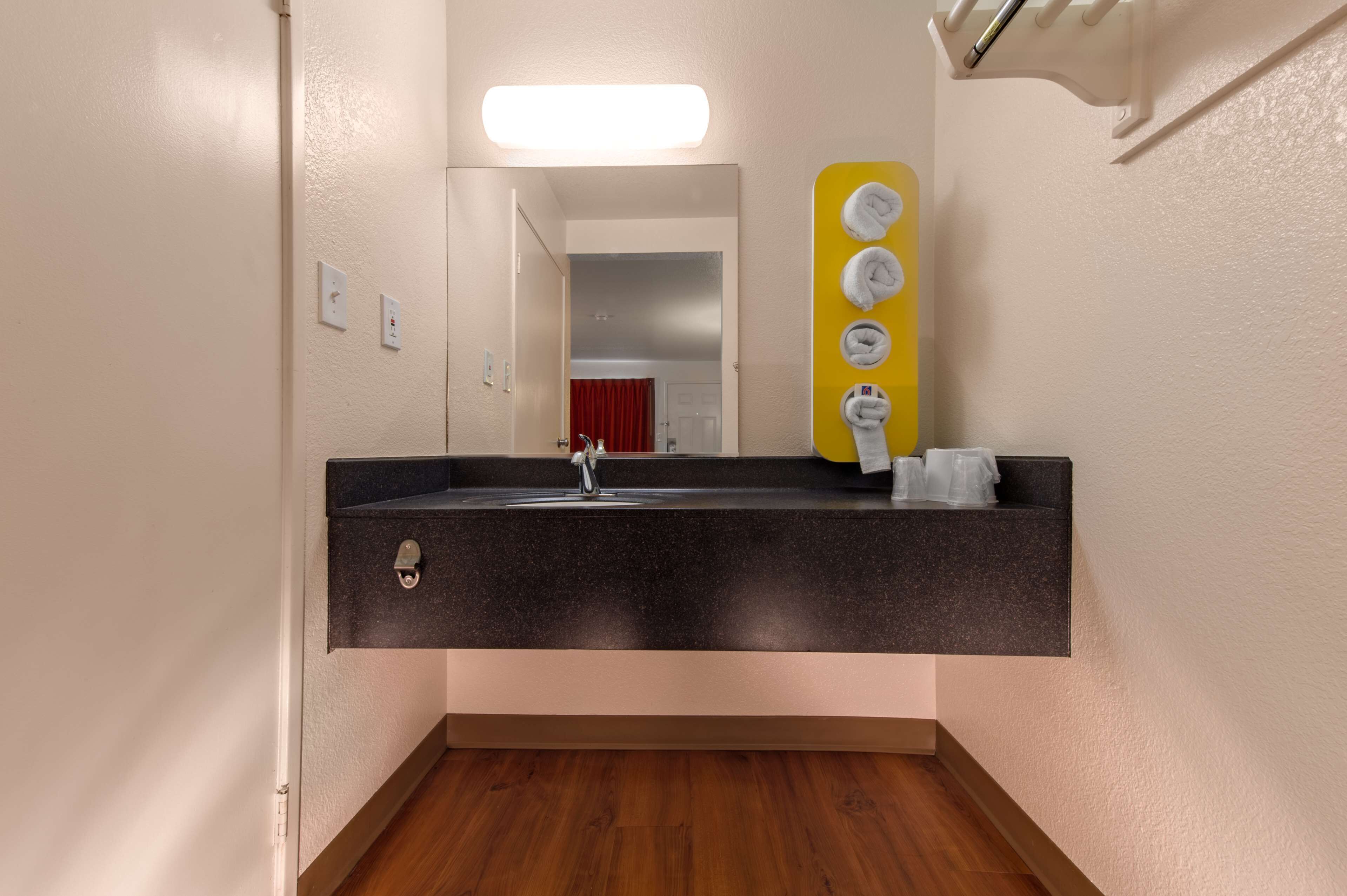 Une salle de bain avec un lavabo en granit foncé, un miroir et un porte-serviettes jaune sur lequel sont posées des serviettes.