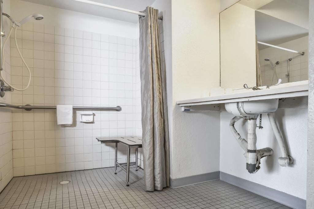 A bathroom with a shower, a toilet, a sink, and a mirror.