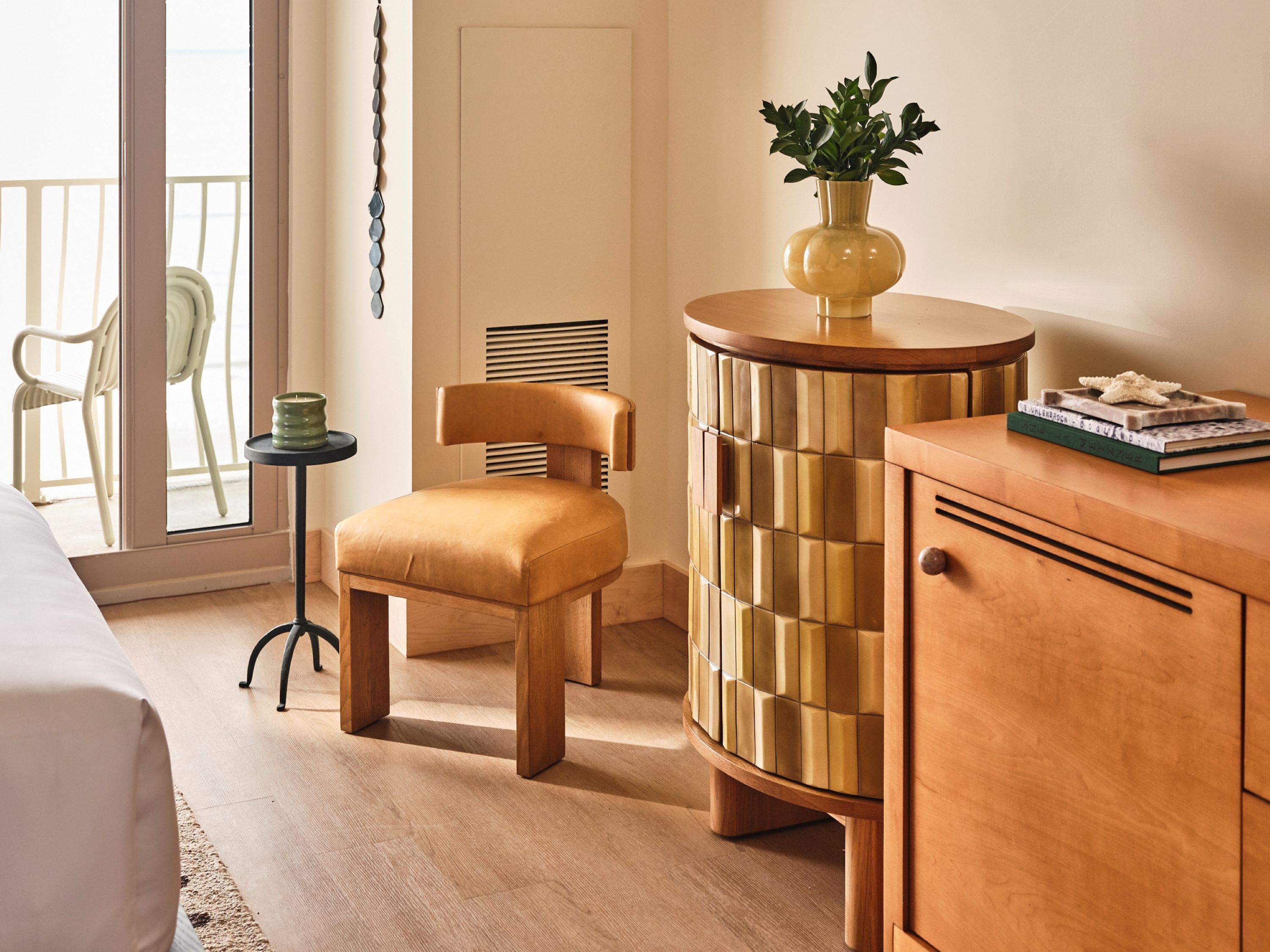 A modern room with a wooden chair, a small table with a plant, and a cabinet with books.