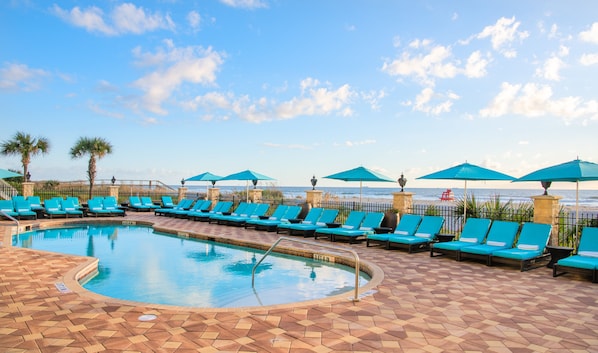 Una piscina al aire libre, sombrillas, sillones reclinables de piscina