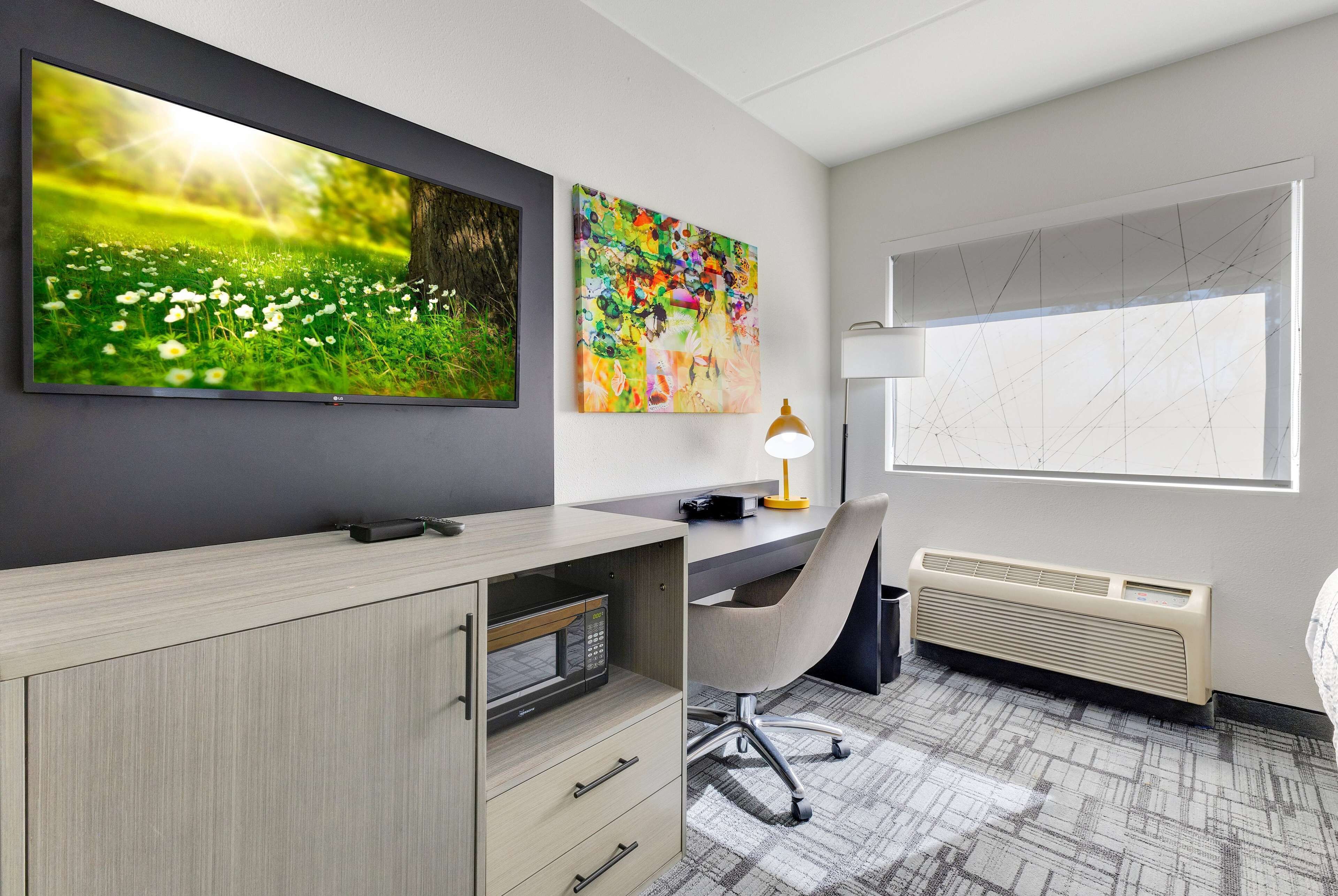 A modern office space with a desk, chair, and a large flat-screen TV.
