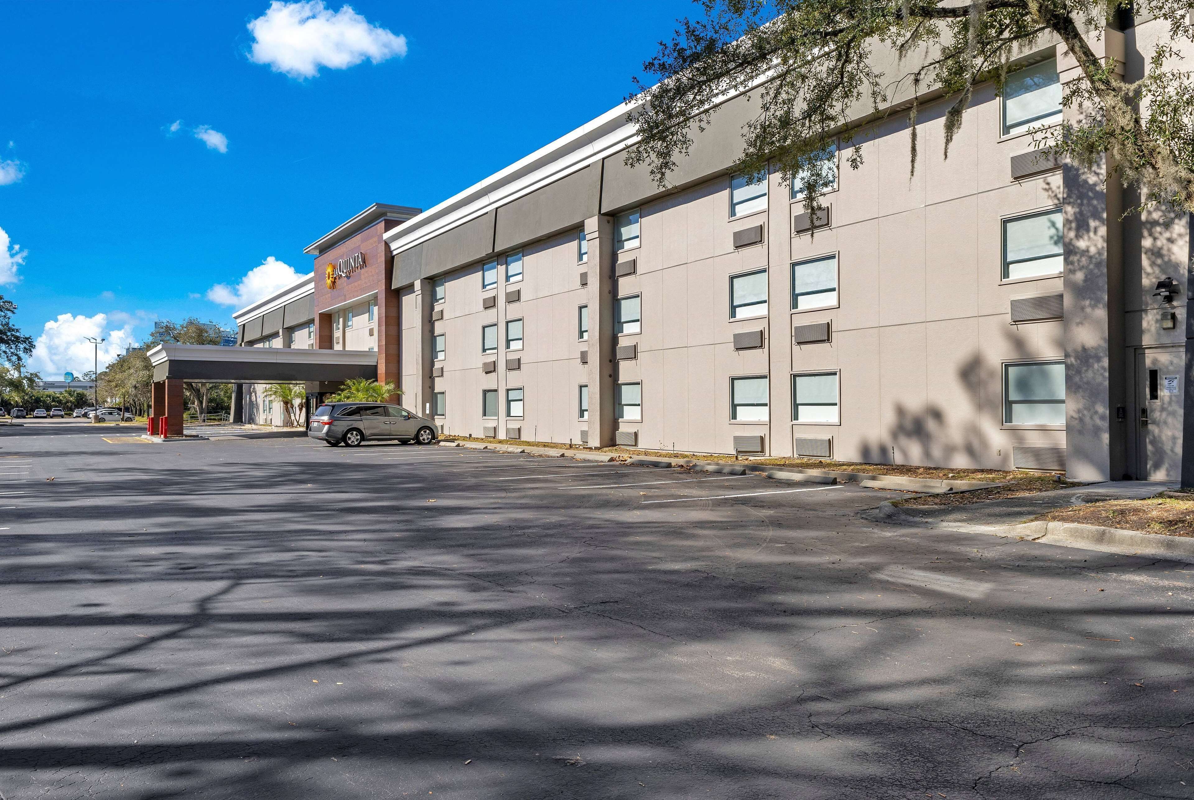 A hotel with a modern facade, multiple windows, and a covered parking area.