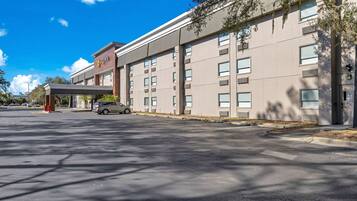 A hotel with a modern facade, multiple windows, and a covered parking area.
