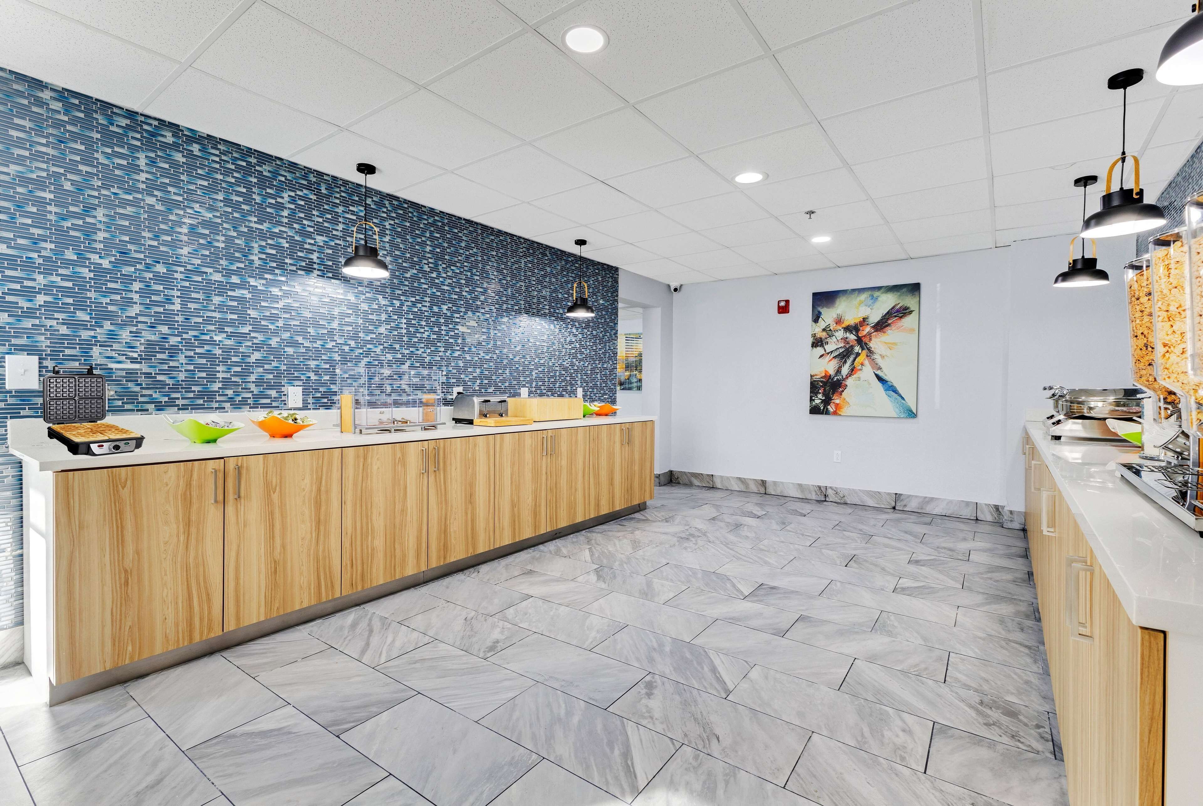 Una cucina moderna con zoccolo blu a mosaico, mobili in legno e pavimento in marmo.