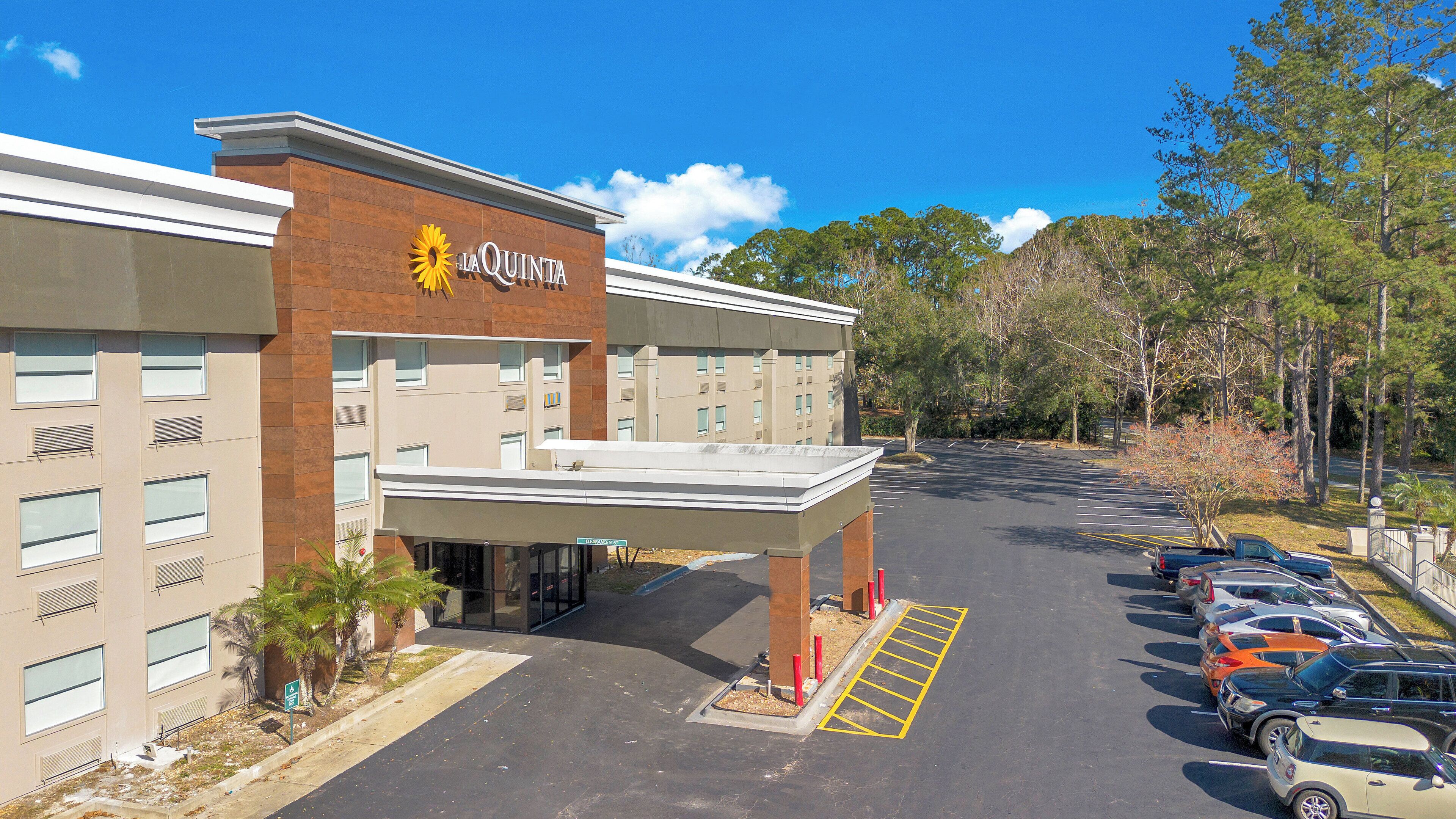 A hotel with a modern design, featuring a prominent entrance and a parking lot with several cars.