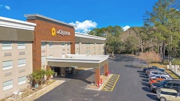 A hotel with a modern design, featuring a prominent entrance and a parking lot with several cars.
