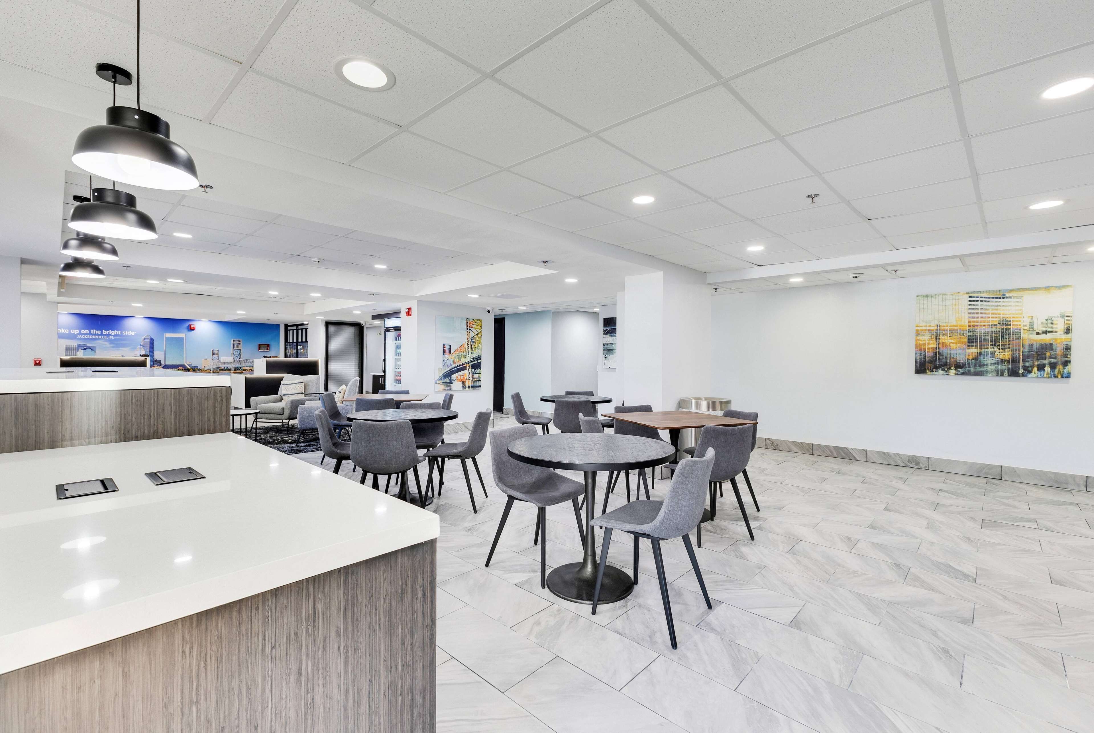 A modern indoor space with a reception area, multiple dining tables, and chairs.