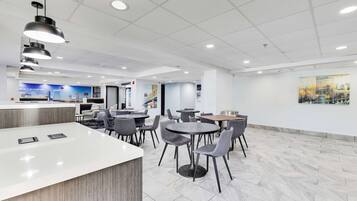 A modern indoor space with a reception area, multiple dining tables, and chairs.