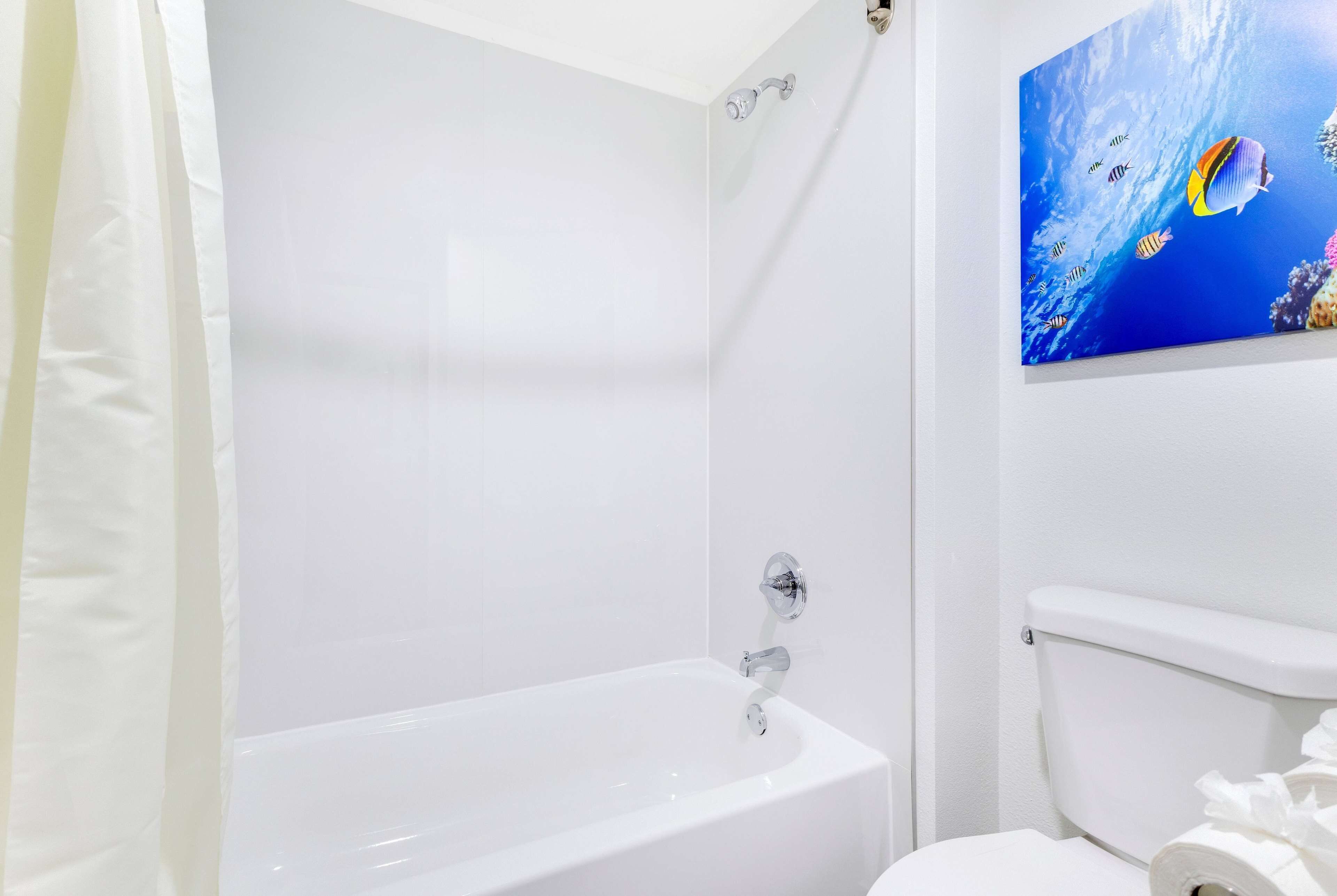A white bathroom with a bathtub, toilet, and a wall-mounted toilet paper holder.