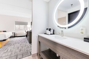 A modern hotel bathroom with a large mirror, white sink, and a vanity. - La Quinta Inn & Suites by Wyndham Jacksonville Mandarin (Jacksonville)