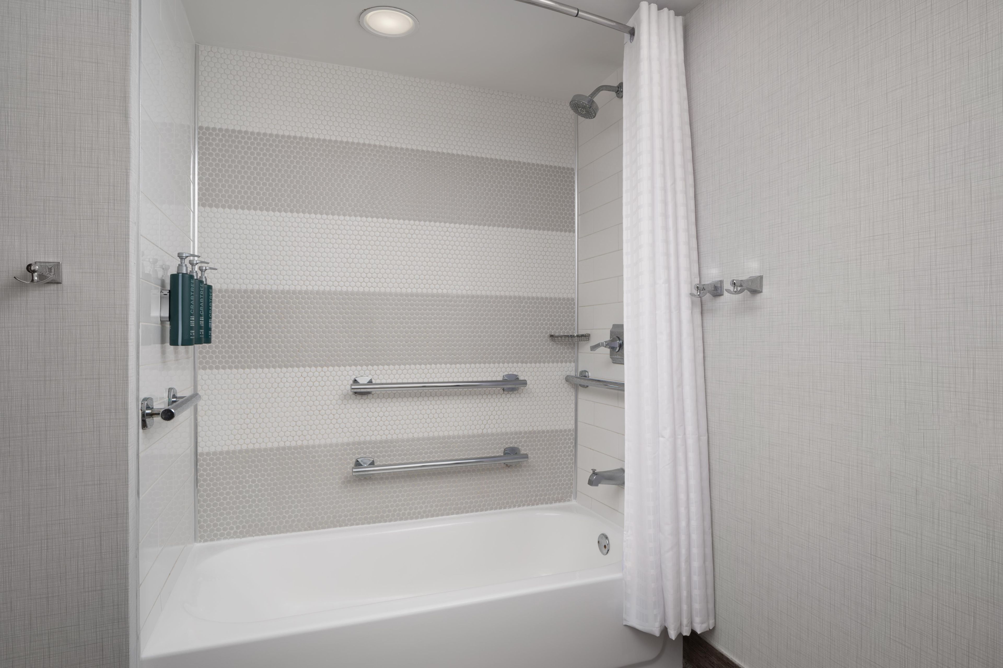 A modern bathroom with a bathtub, shower, and a towel rack.