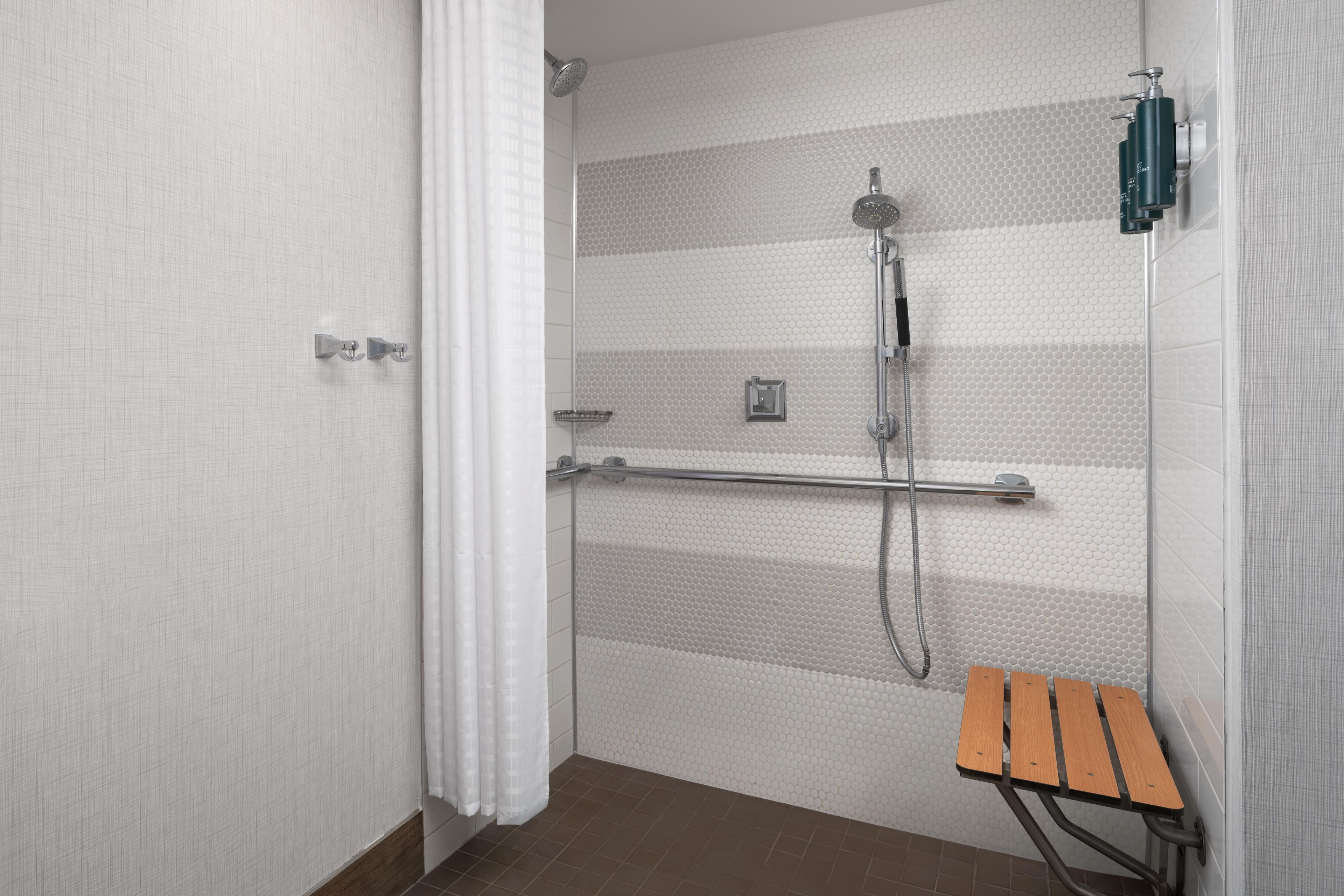 A shower with a rain shower head, a handheld showerhead, and a handheld shower attachment.