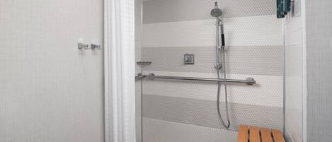 A shower with a rain shower head, a handheld showerhead, and a handheld shower attachment.