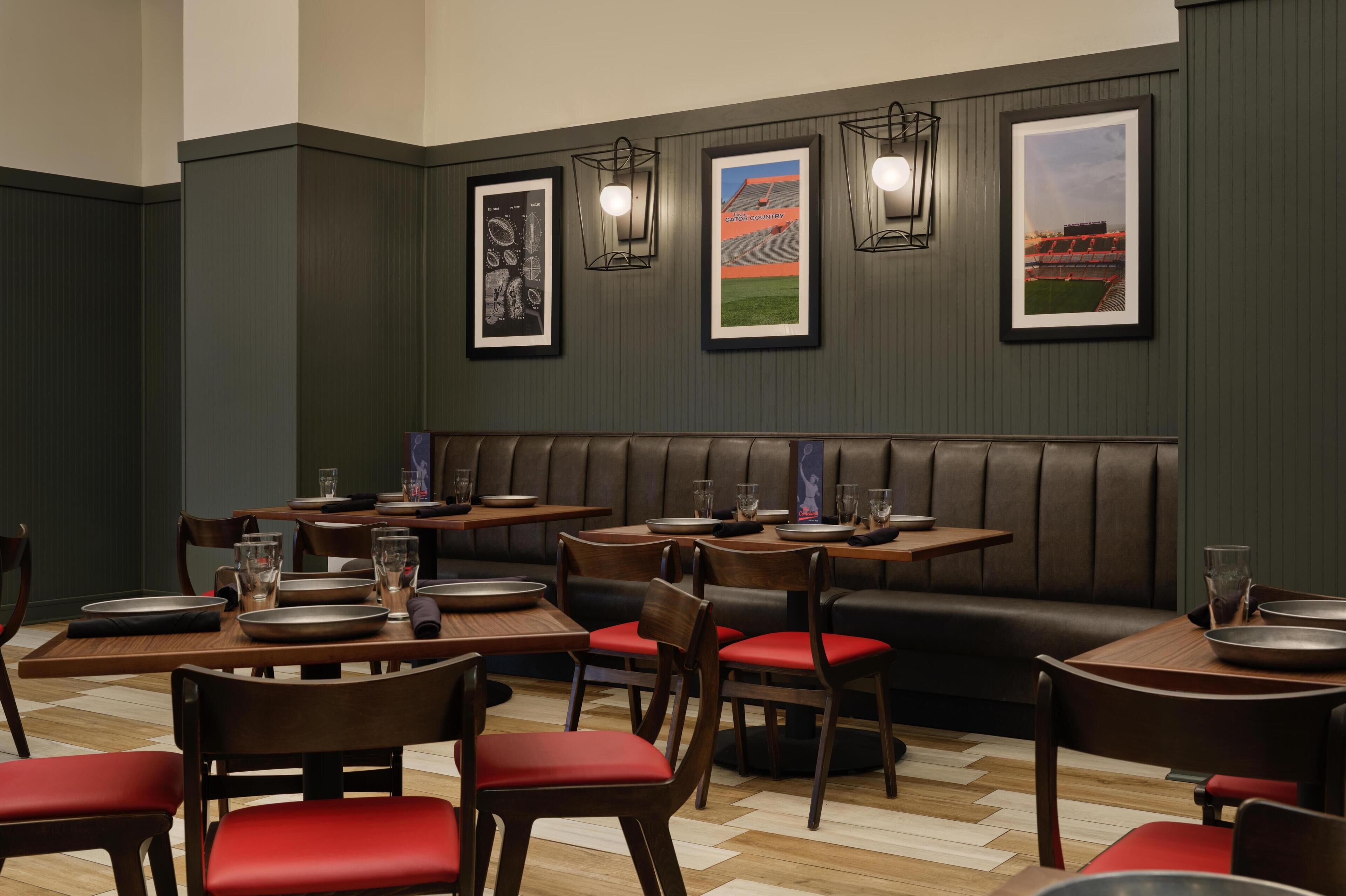 A restaurant with booths, tables, and chairs, featuring framed pictures on the wall.