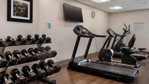 A fitness center with treadmills, elliptical machines, and dumbbells.