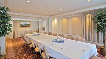 A conference room with a long table, chairs, and a painting on the wall.