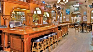 Un espace bar avec des tabourets de bar en bois, un comptoir et un lustre.