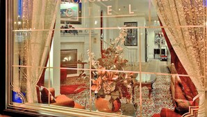 L’intérieur d’un hôtel historique, avec une grande fenêtre, des rideaux richement décorés et un lustre.
