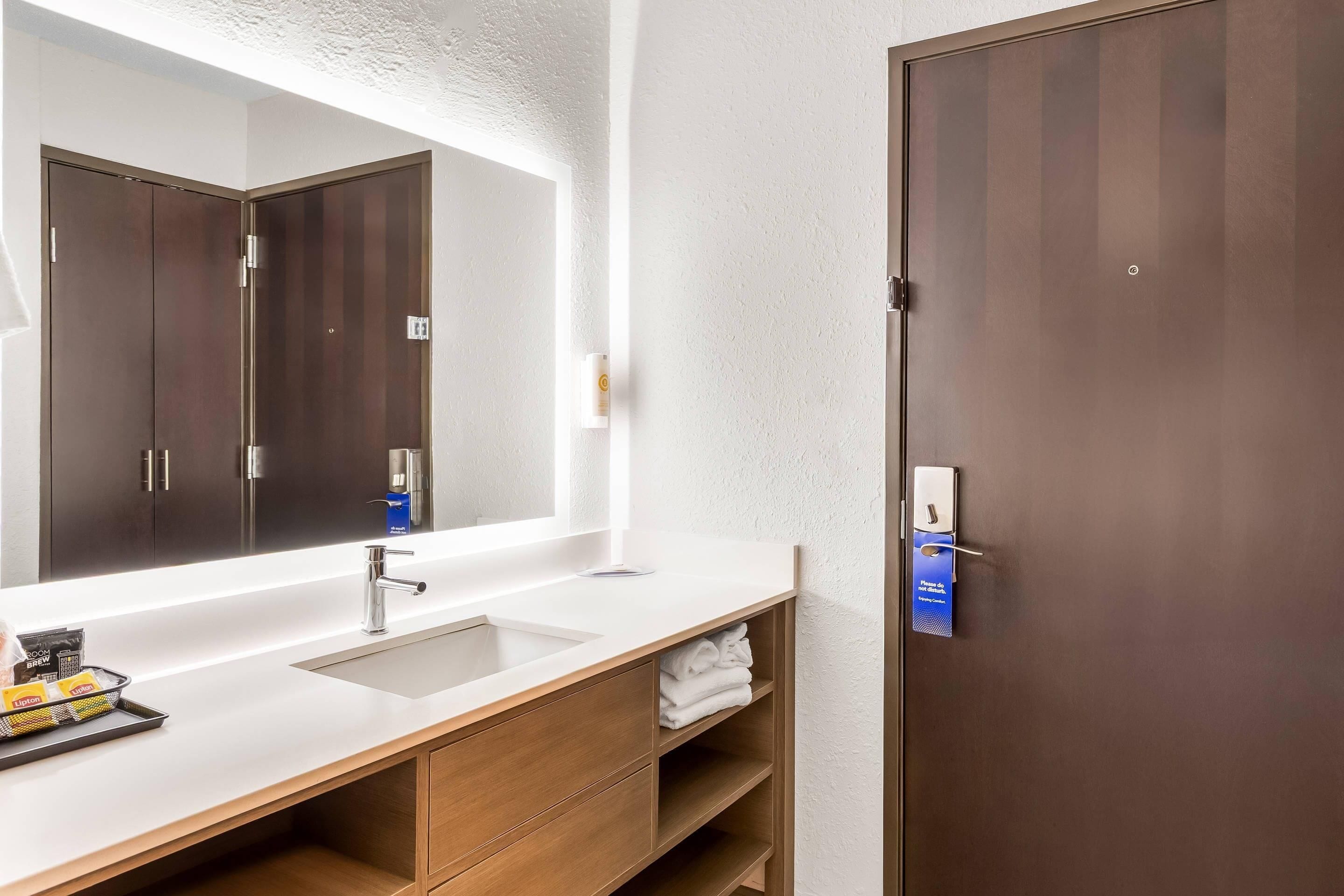 Une salle de bain moderne avec un grand miroir, deux vasques et des meubles en bois.