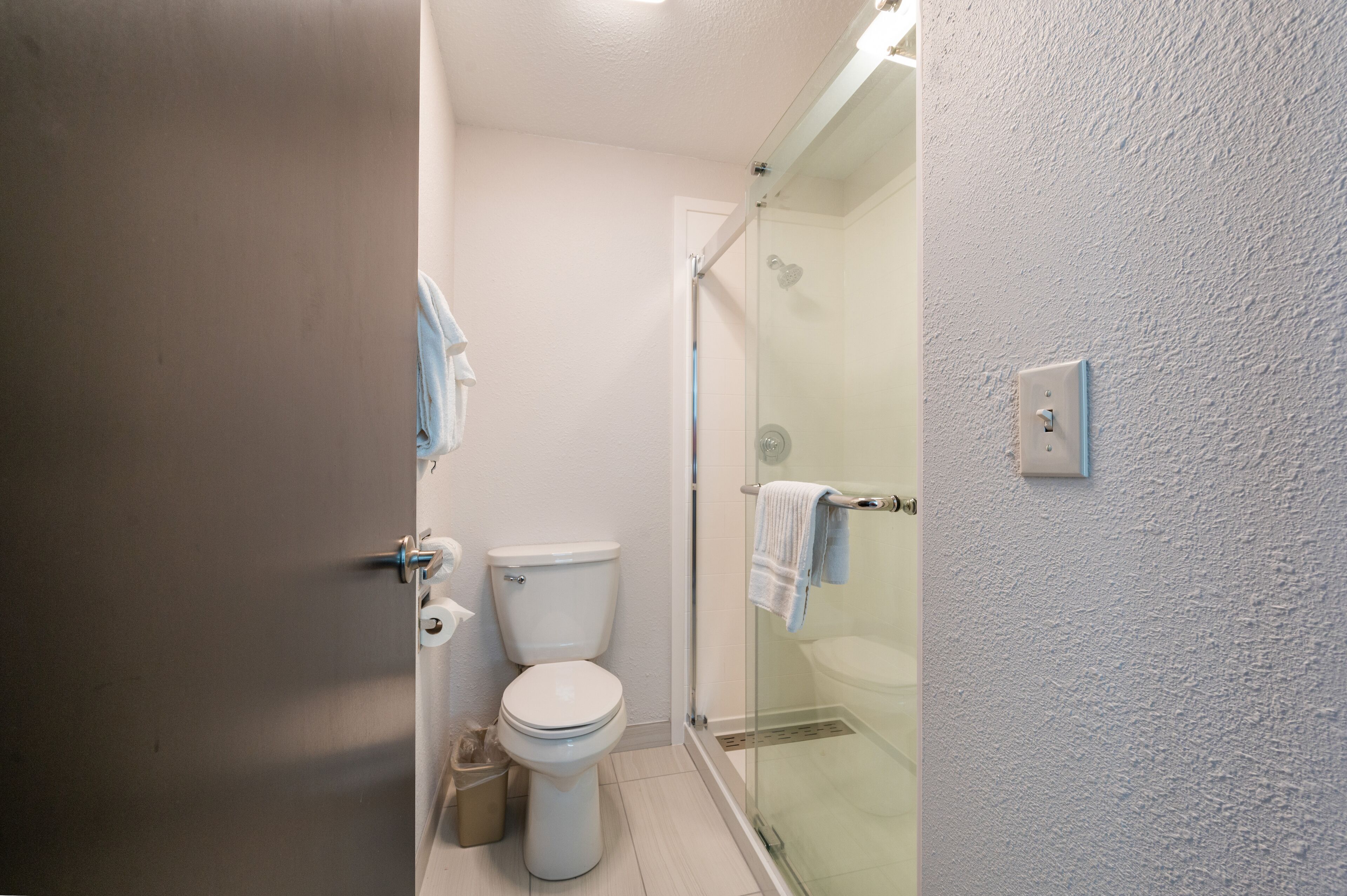 Une salle de bain comprenant des toilettes, une douche à parois de verre et un porte-serviettes.