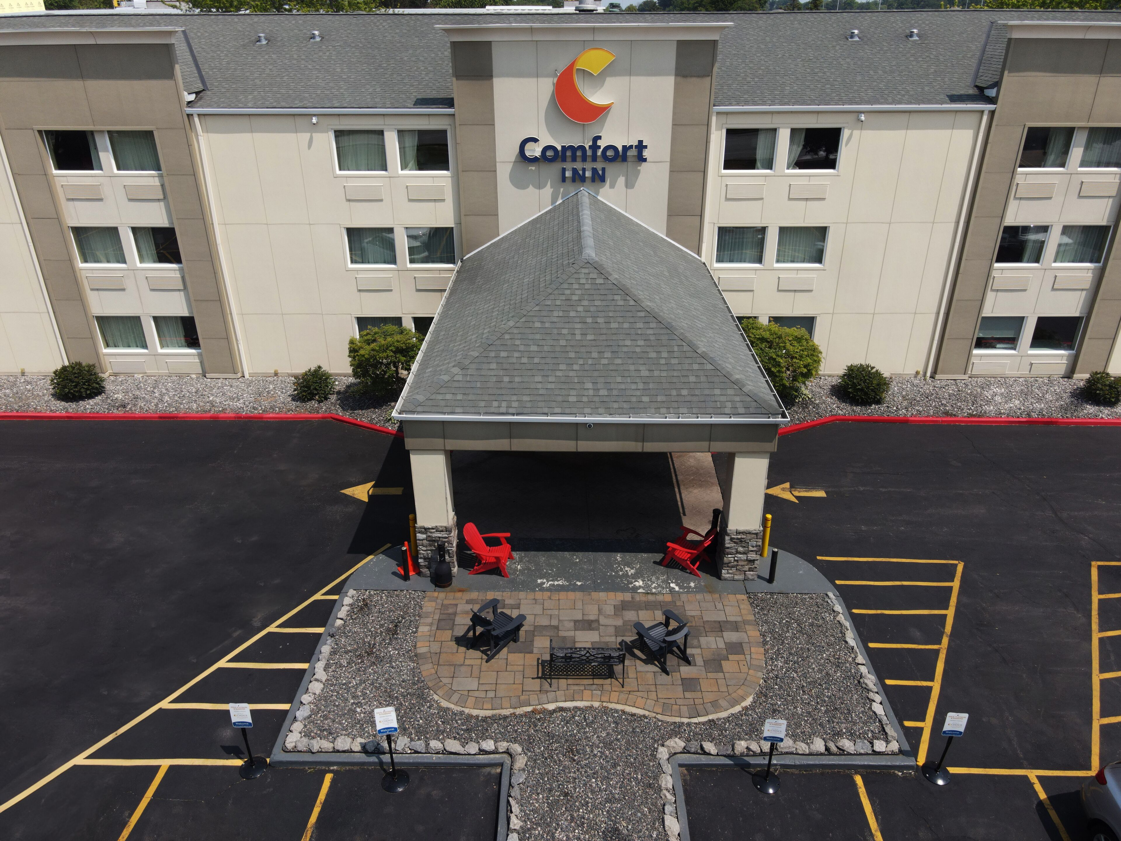 A Comfort Inn hotel with a covered entrance, outdoor seating area, and a parking lot.