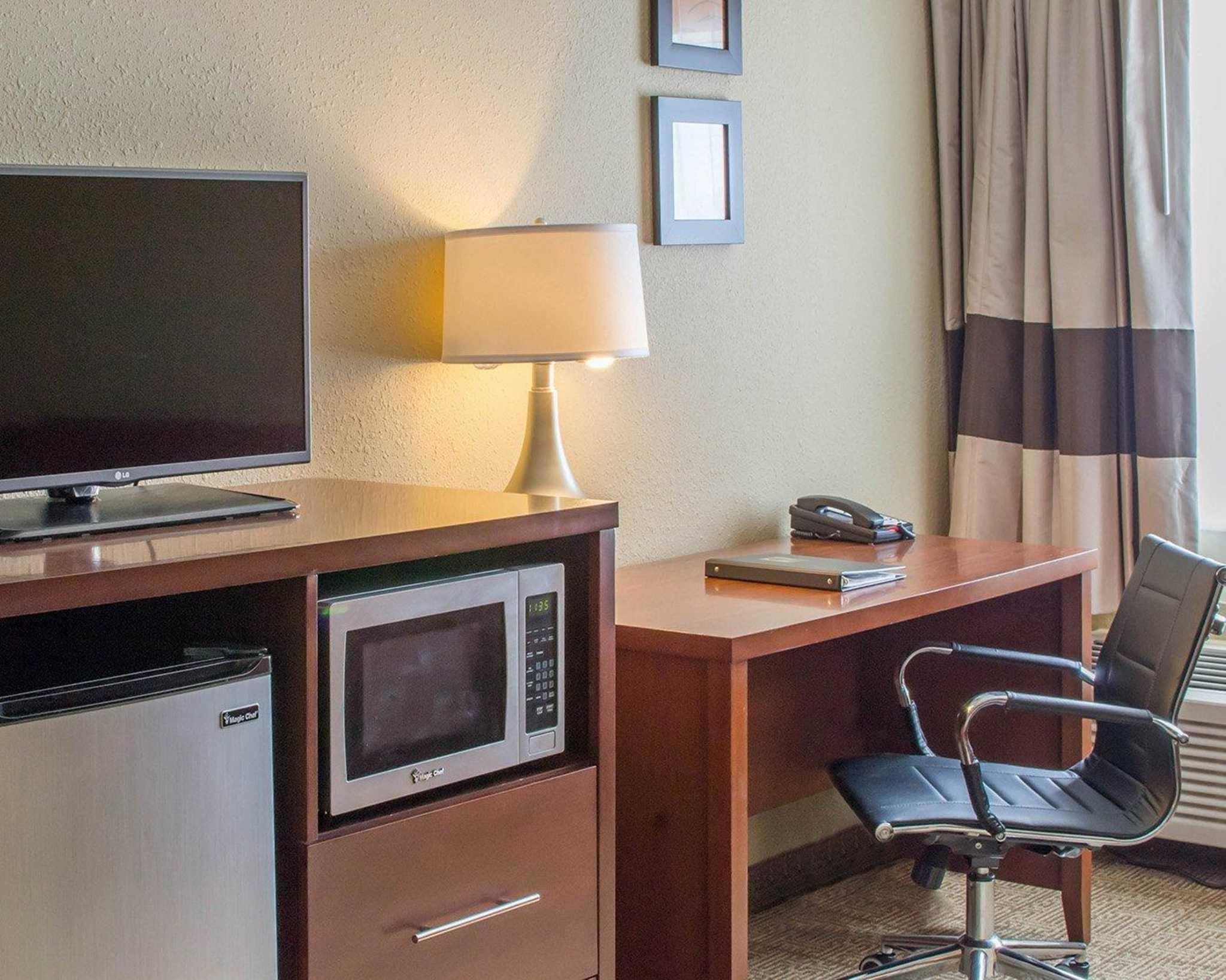 Une chambre d’hôtel équipée d’une télévision à écran plat, d’un four à micro-ondes, d’une lampe, d’un téléphone, d’un bureau et d’une chaise.