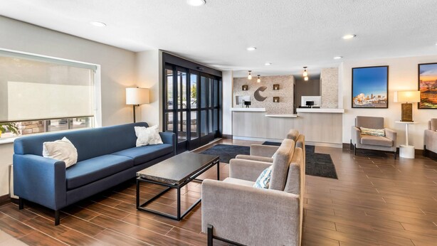 A modern living room with a sofa, armchairs, a coffee table, and a kitchen area with a counter and pendant lights.