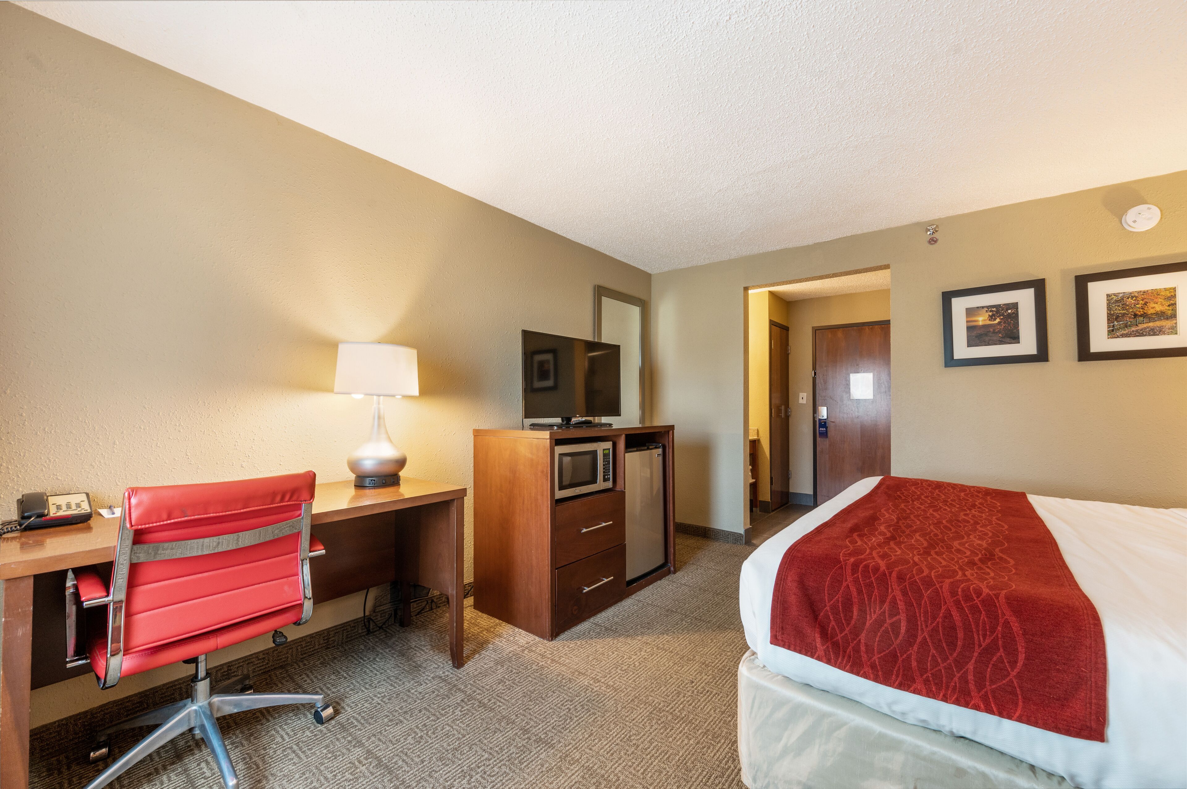 Una habitación de hotel con escritorio, silla, cama y microondas.
