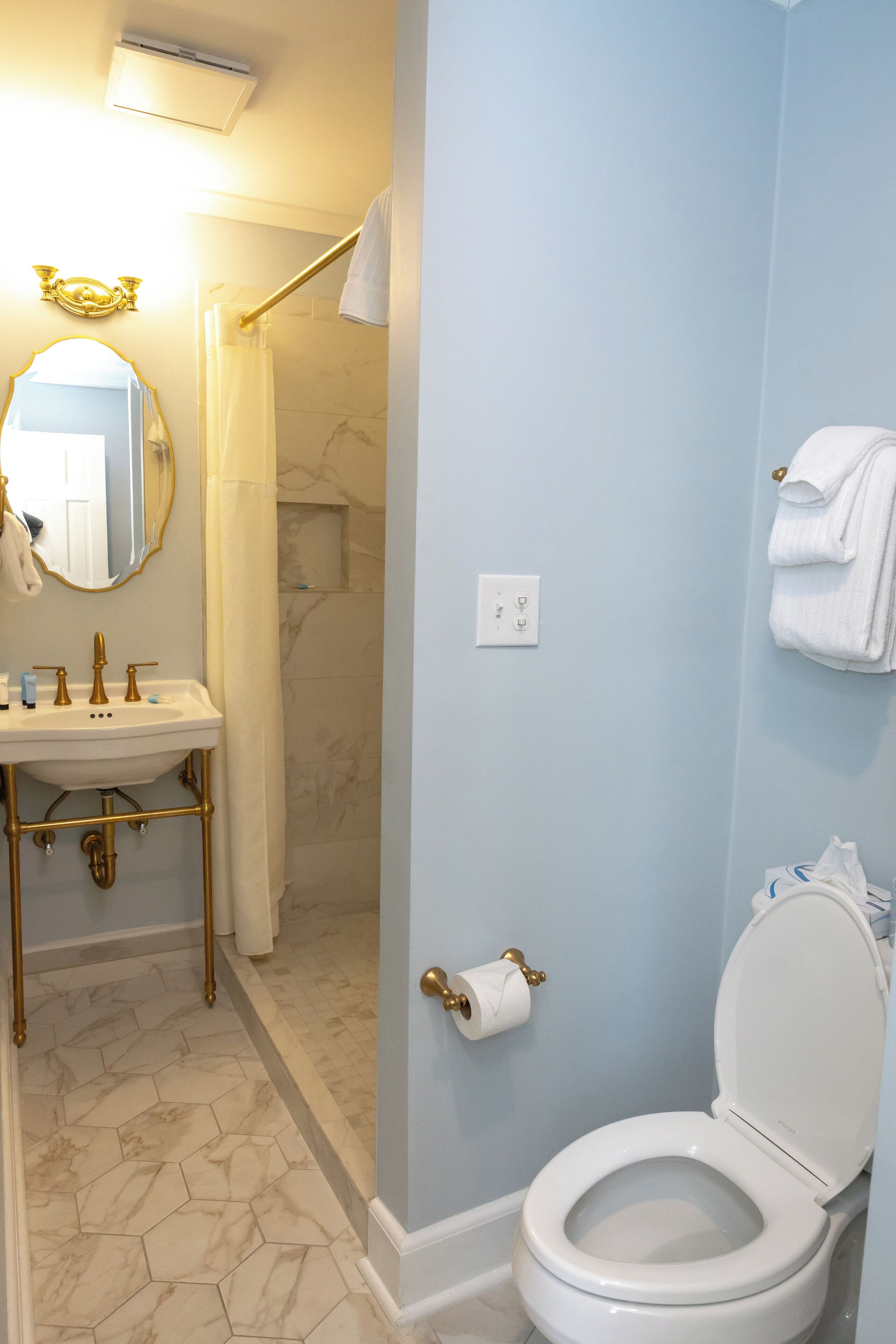 A bathroom with a white sink, gold fixtures, a white toilet, and a shower curtain.