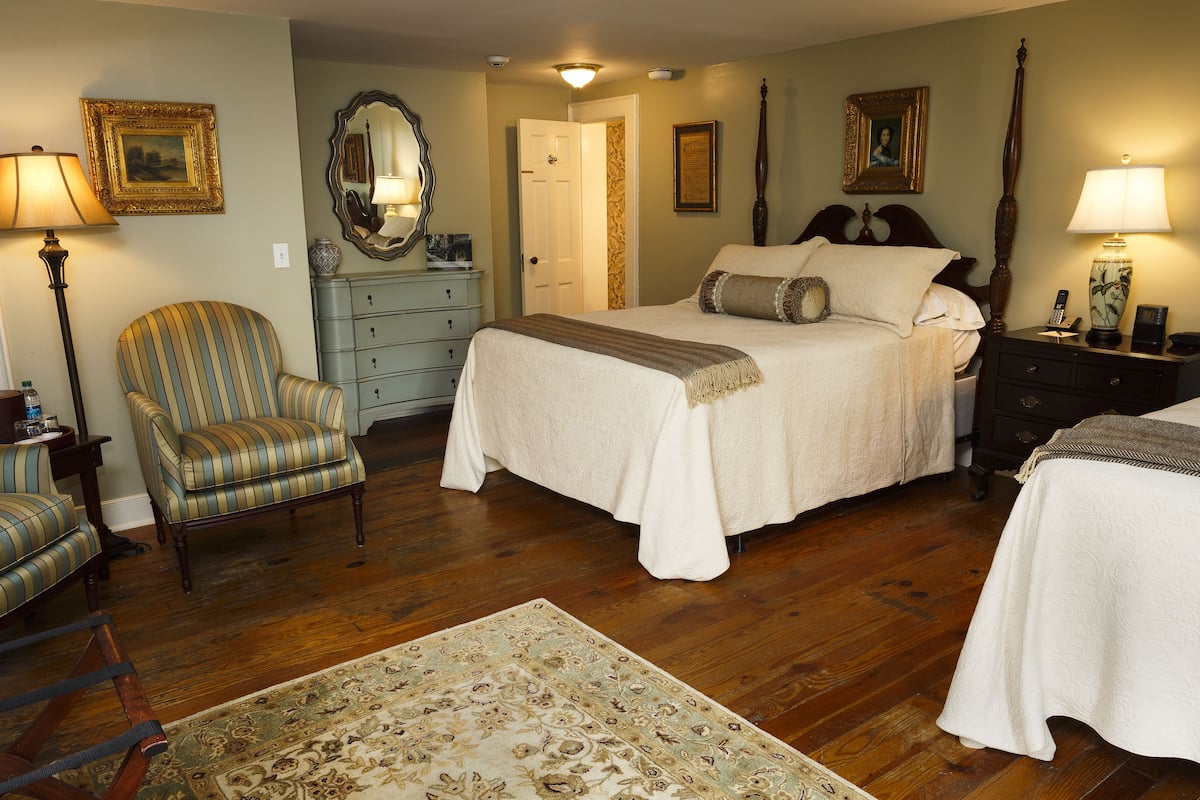 A hotel room with a large bed, a chair, a dresser, and a nightstand.