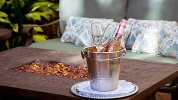 A metal bucket with a bottle and glasses on a table with a decorative doily.