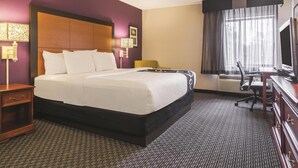 A hotel room with a large bed, a desk with a chair, a television, and a window with curtains. - Wingate by Wyndham Brunswick GA / I-95 (Brunswick)