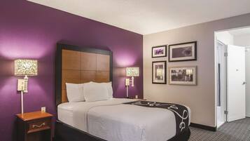 A hotel room with a bed, bedside tables, wall-mounted lamps, and framed pictures.