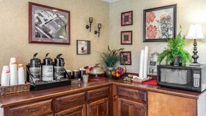 Una cocina con estación de café, microondas y varios objetos decorativos.