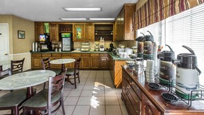 Una cocina con armarios de madera, una estación de café y un comedor con mesa y sillas.