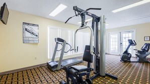 Un gimnasio con máquinas de cardio, equipo de entrenamiento con pesas y una alfombra estampada.