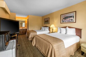 A hotel room with two beds, a television, a desk, and a mirror.