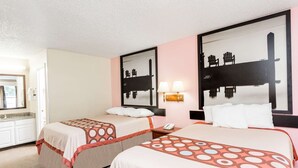 Une chambre d’hôtel avec deux lits, une salle de bain, un miroir et une table de chevet avec une lampe.
