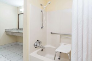 A bathroom with a shower, a sink, and a grab bar.