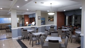 A restaurant with multiple tables and chairs, a bar area, and a view of the outside.
