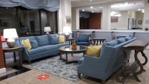 A modern living room with a blue sofa, armchairs, a coffee table, and a dining table.